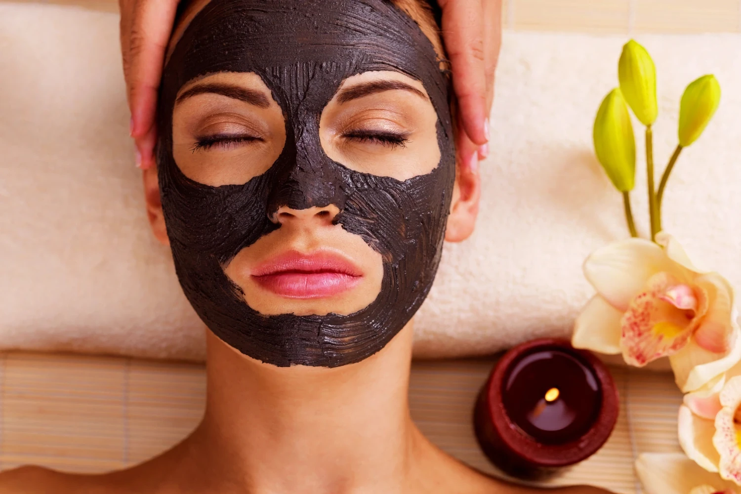 Woman wears a dark facial mask during a customized facial treatment.