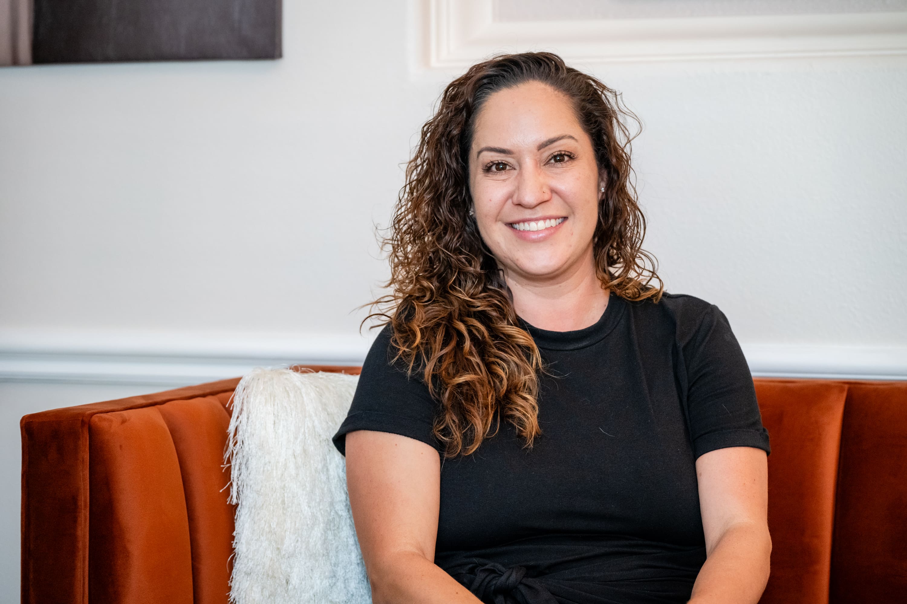 A woman sitting on top of an orange couch.